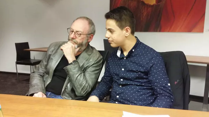 Liam Cunningham und Hussam aus Syrien sitzen zusammen World Vision