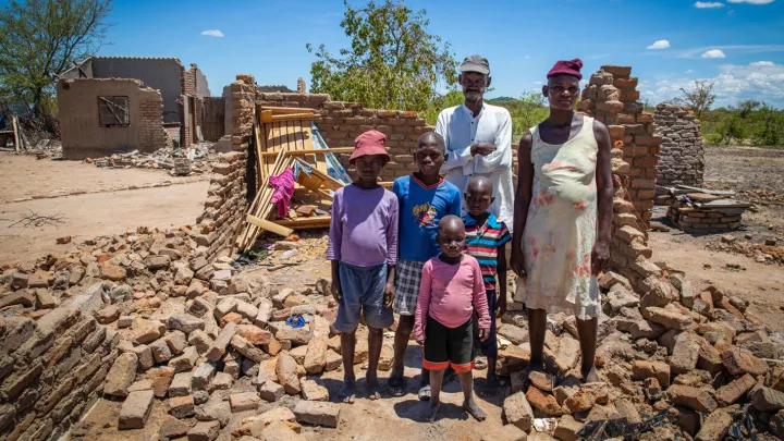 Familie steht vor dem Haus das durch den Zyklon Idai zerstört wurde