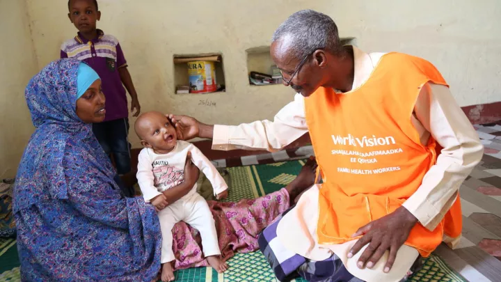 Ein World Vision Mitarbeiter untersucht ein Baby in einer Gesundheitsstation