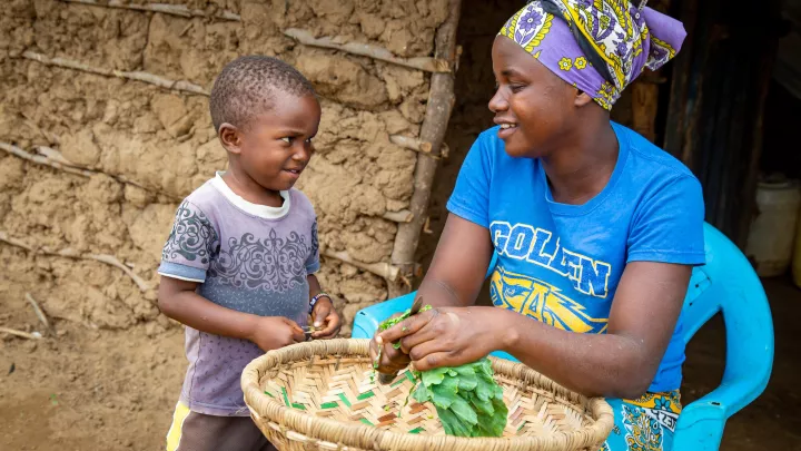 Kleinbäuerin mit Kleinkind bei Lebensmittel-Verarbeitung