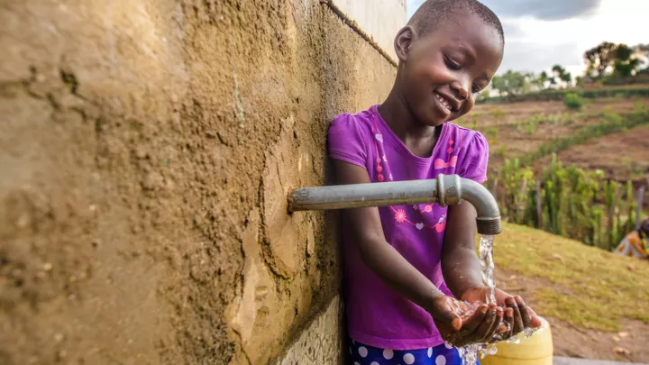 Kamama schöpft Wasser aus einem Wasserkiosk