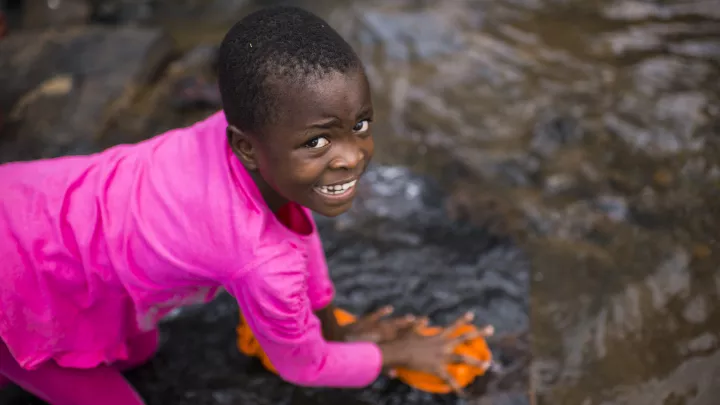 Patenkind Praise schaut beim Wäschewaschen auf. 