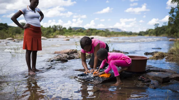 Praise und ihre Mutter waschen Kleidung im Fluss. 