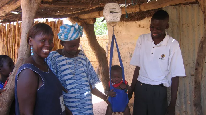 2006: Ein Kleinkind wird von einem Patenbetreuer gewogen