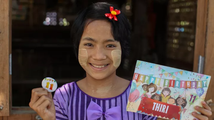 Patenkind Thiri aus Myanmar hält die Geburtstagskarte ihres Paten.