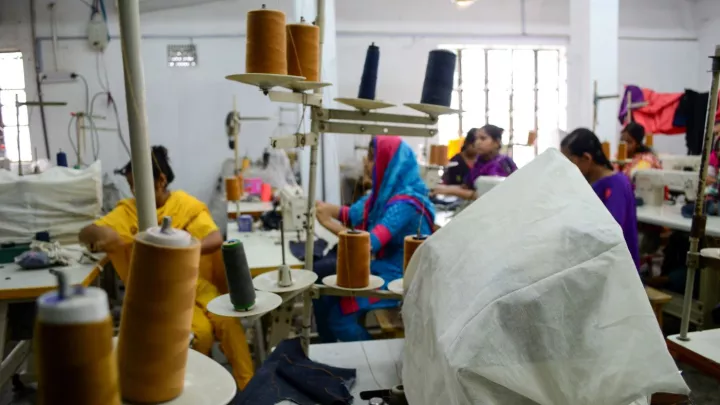 Kinderarbeiterin in einer Textilfabrik an der Nähmaschine