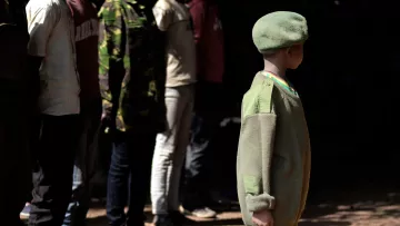 Kind in Uniform vor einer Reihe Soldaten