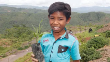 Junge mit Setzling zur Wiederbegrünung