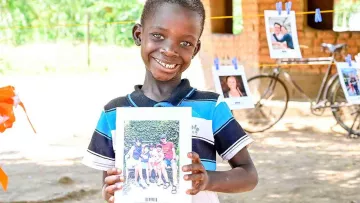 afrikanischer Junge mit Bild von Paten in der Hand