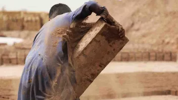 Afghanischer Junge, der Steine schleppt