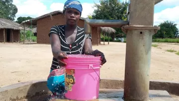 Frau vor Pumpbrunnen in Mosambik