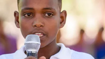 Junge aus Afrika mit Mikrofon in der Hand setzt sich für Kinderrechte ein