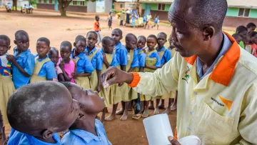 World Vision Mitarbeiter gibt Schulkindern Medizin