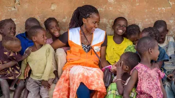 Gemeinsam mit World Vision den Kinder auf der Welt helfen: Mitarbeiterin lacht gemeinsam mit Kindern in Afrika