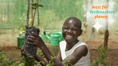 Patenkind hält Baumsetzling in der Hand