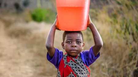 Kind trägt einen Wassereimer