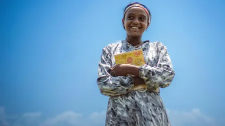 Mädchen aus Äthiopien mit einem Schulbuch in den Armen