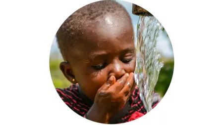 Kind in Ghana an trinkt sauberes Wasser aus der Leitung