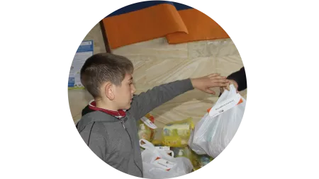 Ein Junge aus Armenien bekommt eine Tüte Nahrungsmittel.