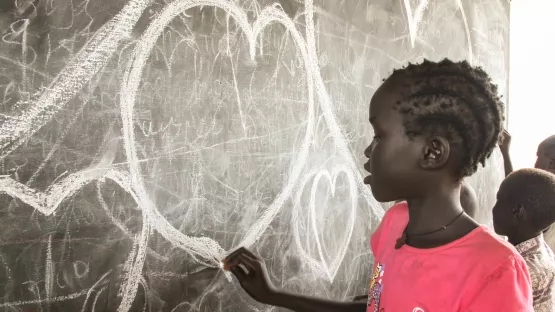 Mädchen malt Herz an eine Tafel