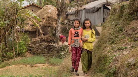 Zwei Schülerinnen auf dem Weg durch ihr Dorf