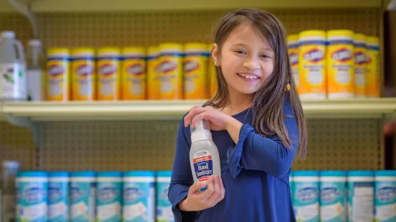 Amerikanisches Mädchen hält eine Flasche Desinfektionsmittel
