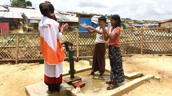 World Vision Mitarbeitern zeigt Kindern das richtige Händewaschen
