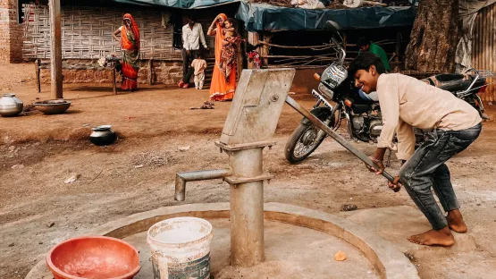 Junge in Indien pumpt sauberes Wasser