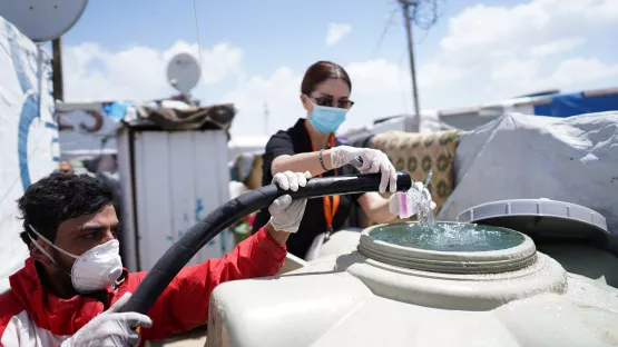 World Vision-Helfer füllen einen Wassertank in einem Flüchtlingslager