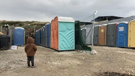Kind vor Toiletten im Lager Kara Tepe