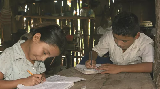 Zwei Kinder sitzen an ihren Schulaufgaben