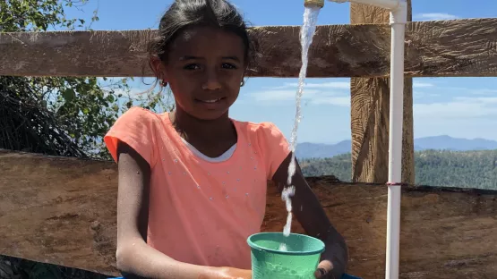 Mädchen zapft sauberes Wasser aus einem Hahn