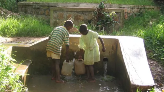 Kinder holen an einem alten Brunnen Wasser