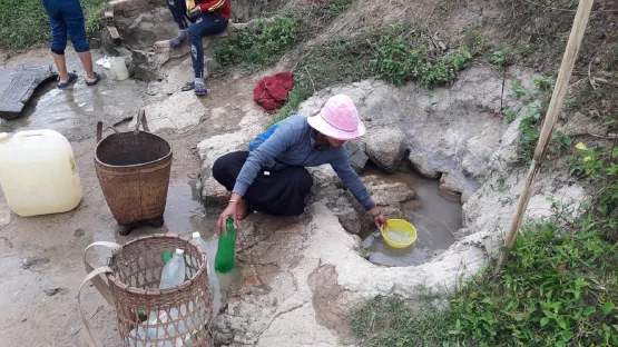 Frauen holen Wasser aus einem Wasserloch