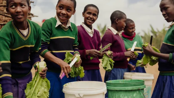 Kinder aus Tansania beteiligen sich an der Zubereitung von Schulmahlzeiten